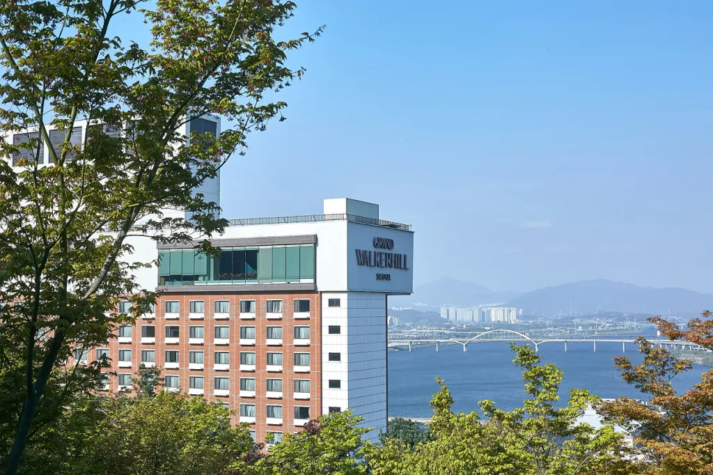 나무 사이로 보이는 그랜드 워커힐 서울 외관과 한강