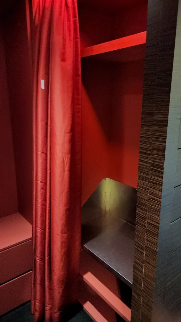 붉은 커튼으로 마감한 샤워가운과 짐 보관 공간