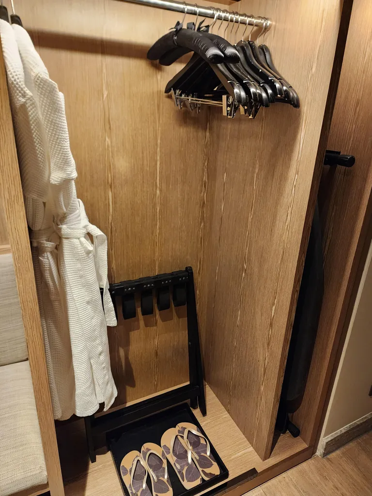 옷걸이와 가운, 캐리어 거치대, 쪼리가 놓인 옷장